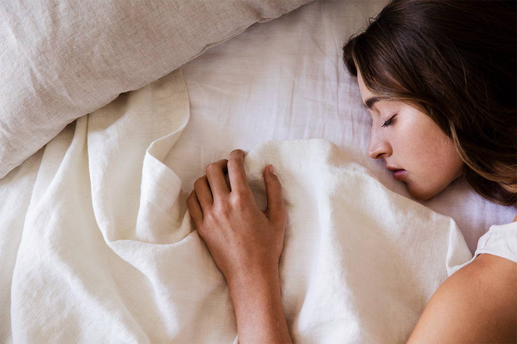 woman sleeping in bed with Cultiver linen bedding