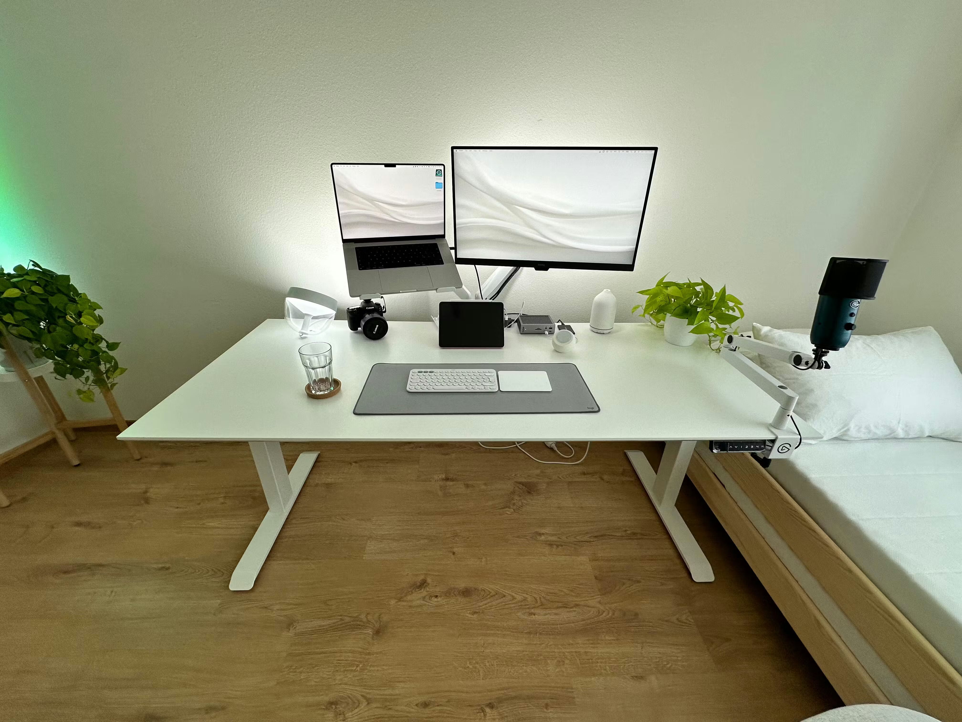 Elektrisch höhenverstellbarer Bürotisch Elevate von ofinto in der Tischplatten-Farbe Weiss und Beine aus Weiss in einem Homeoffice mit Computer, Bildschirm, Kaffeetasse und Tastatur auf dem Tisch