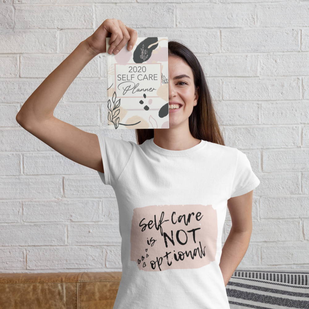 Image of a woman holding El and Al's 2020 Self Care Planner while wearing the bonus t-shirt