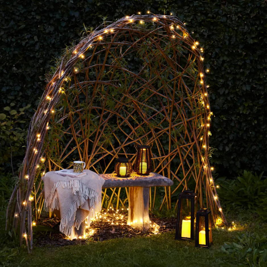 Warm white fairy lights and lanterns surrounding a woven pod seat