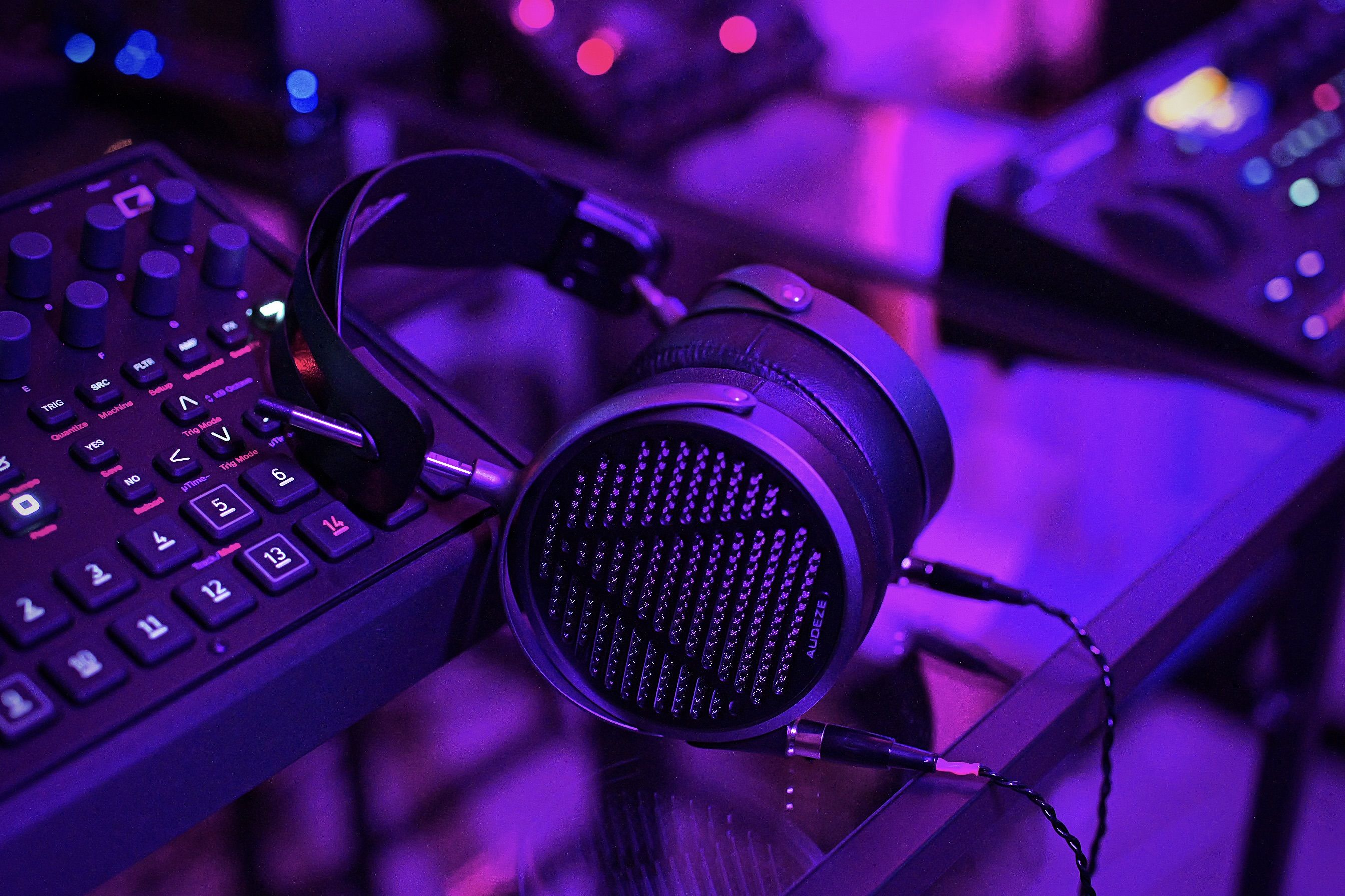 Audeze MM-500 headphones in a purple light one a glass table of a mixing room leaning on gear