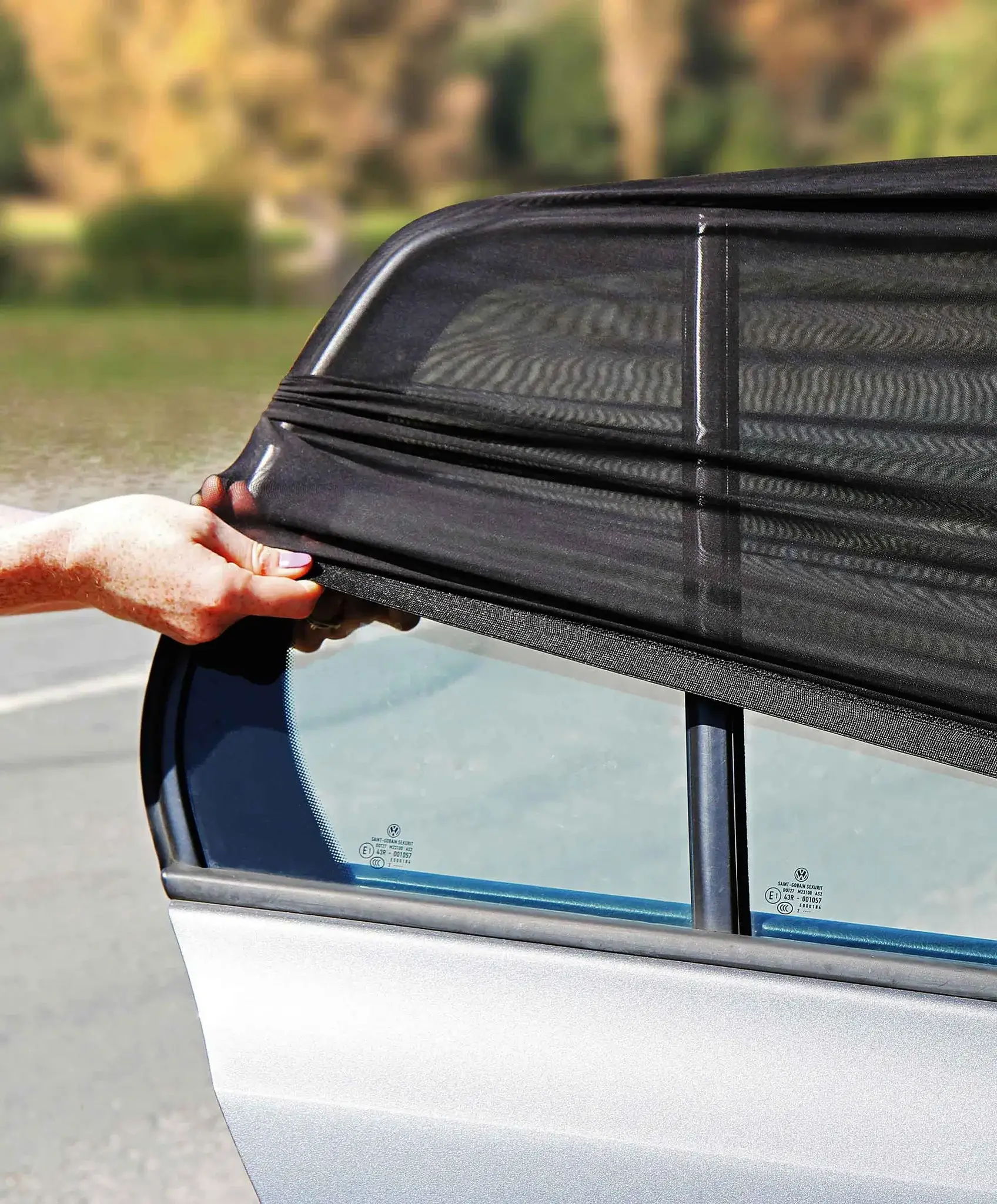 Person installing a window shade on a car door.