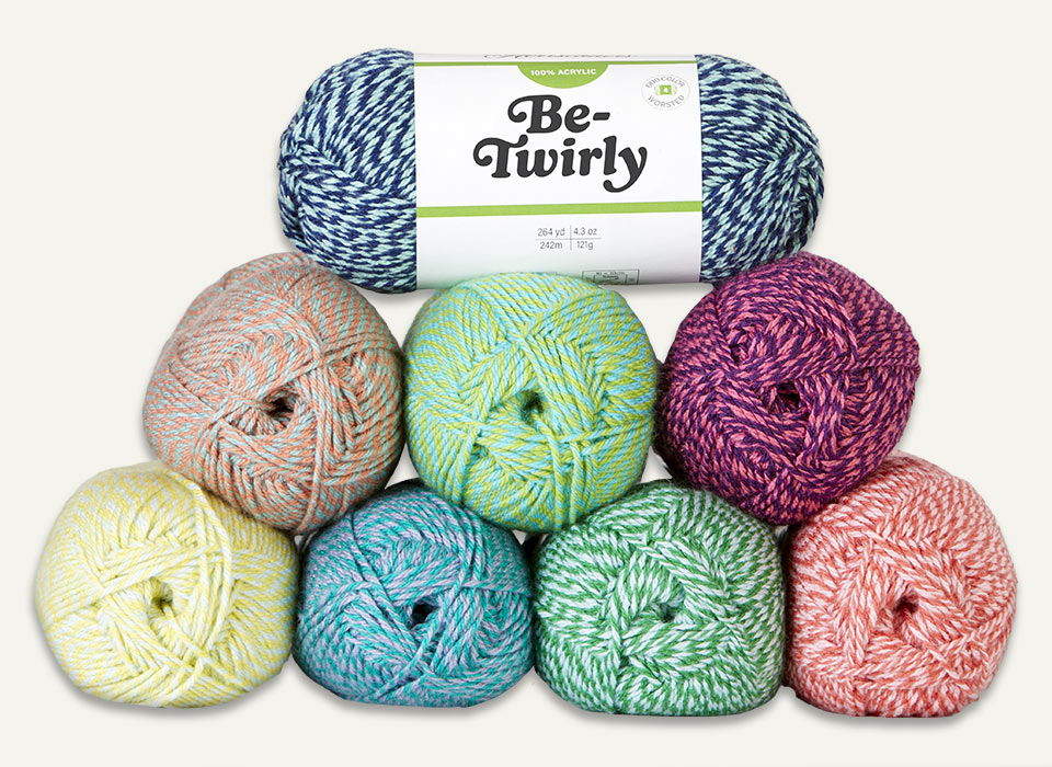 Colorful Herrschners Be-Twirly yarn balls arranged in a stack with a label.