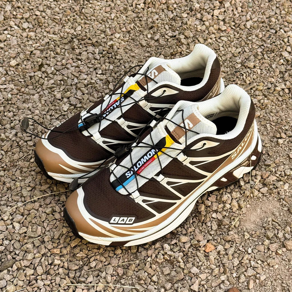 A pair of brown and white athletic shoes on gravel.
