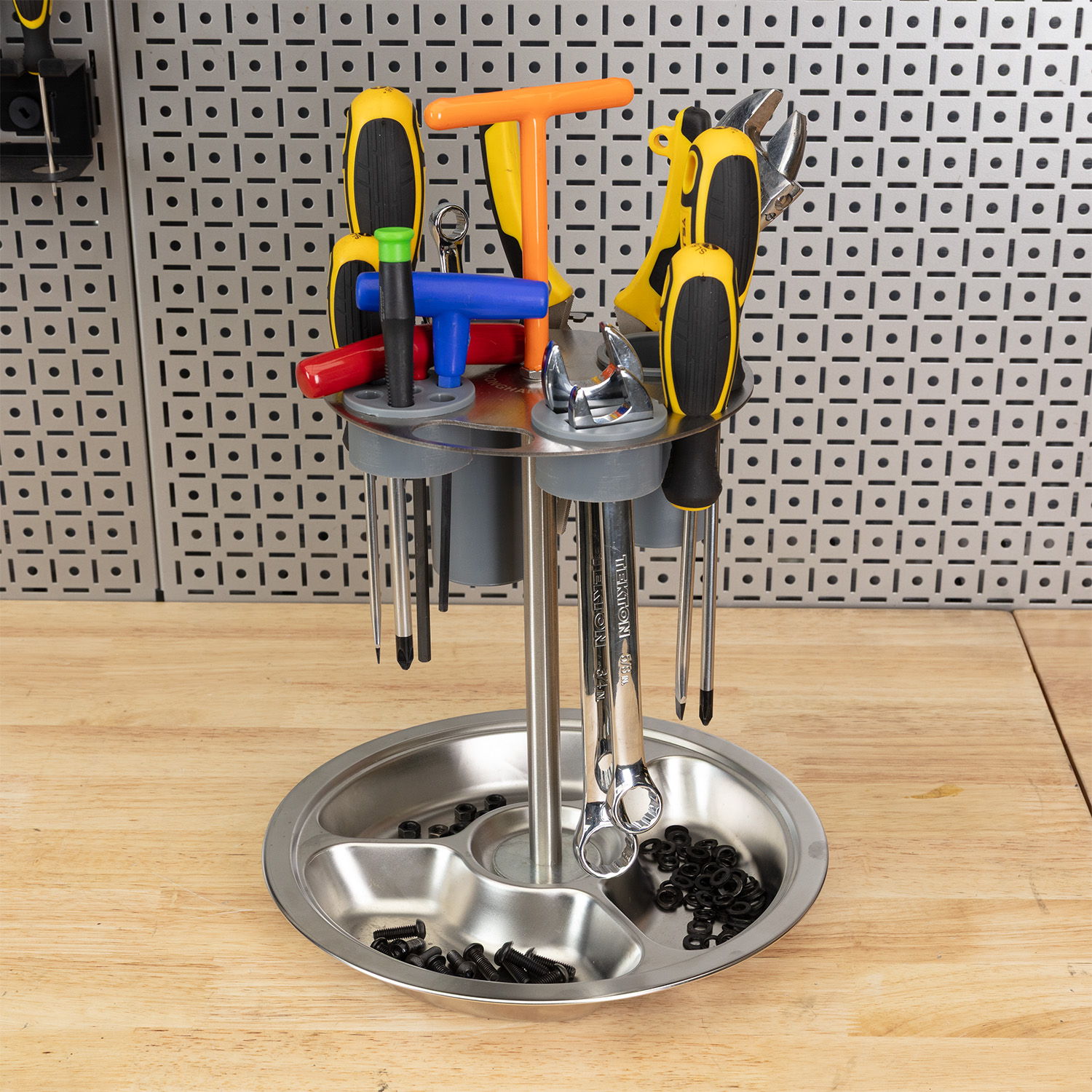 A variety of tools organized in a metal holder on a wooden surface.