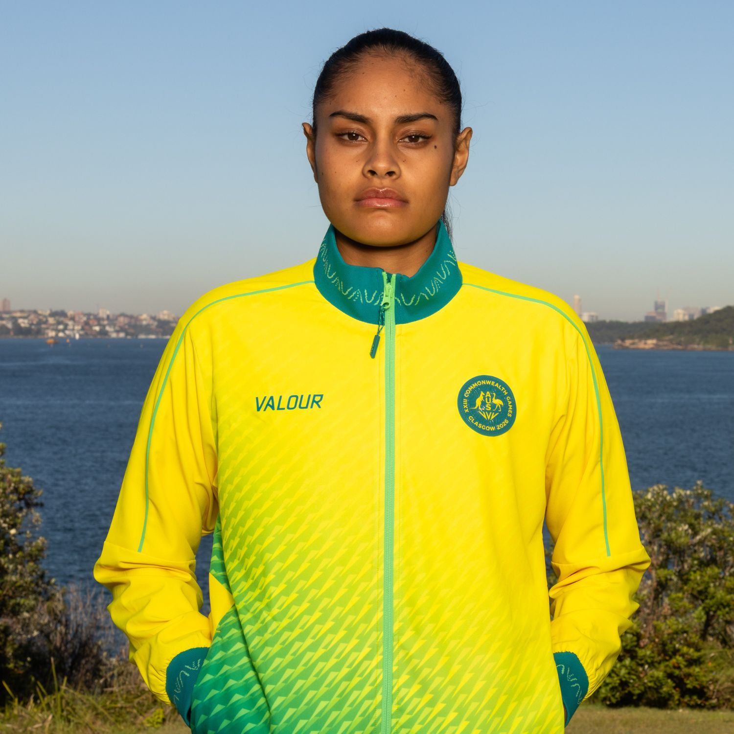 Athlete in a yellow and green jacket by the water.