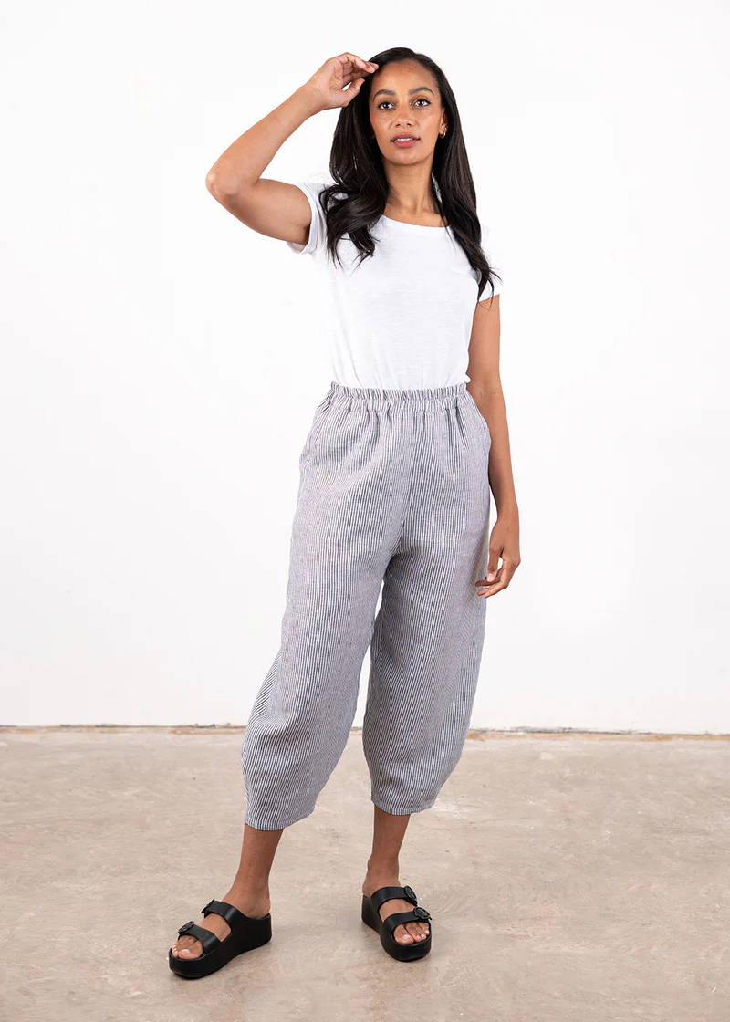 A model wearing a white top with a pair of grey and white striped linen trousers and chunky black platform slides