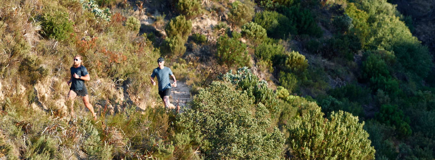 Two male runners running on a mountain trail
