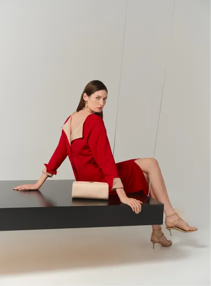 A woman in a red dress poses on a black table.