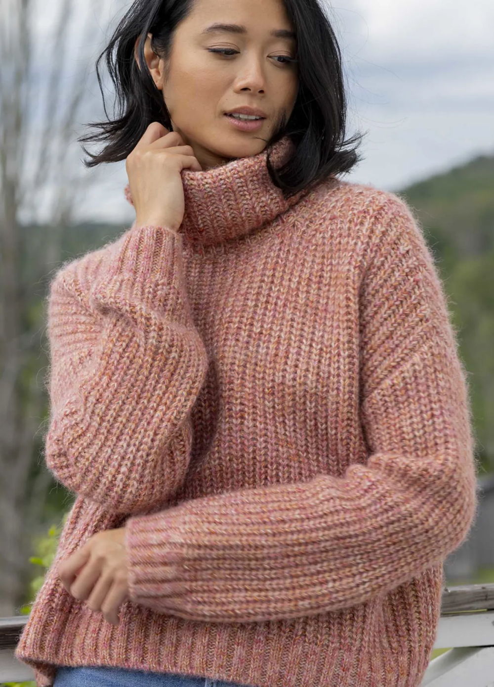 A woman in a cozy pink sweater outdoors.