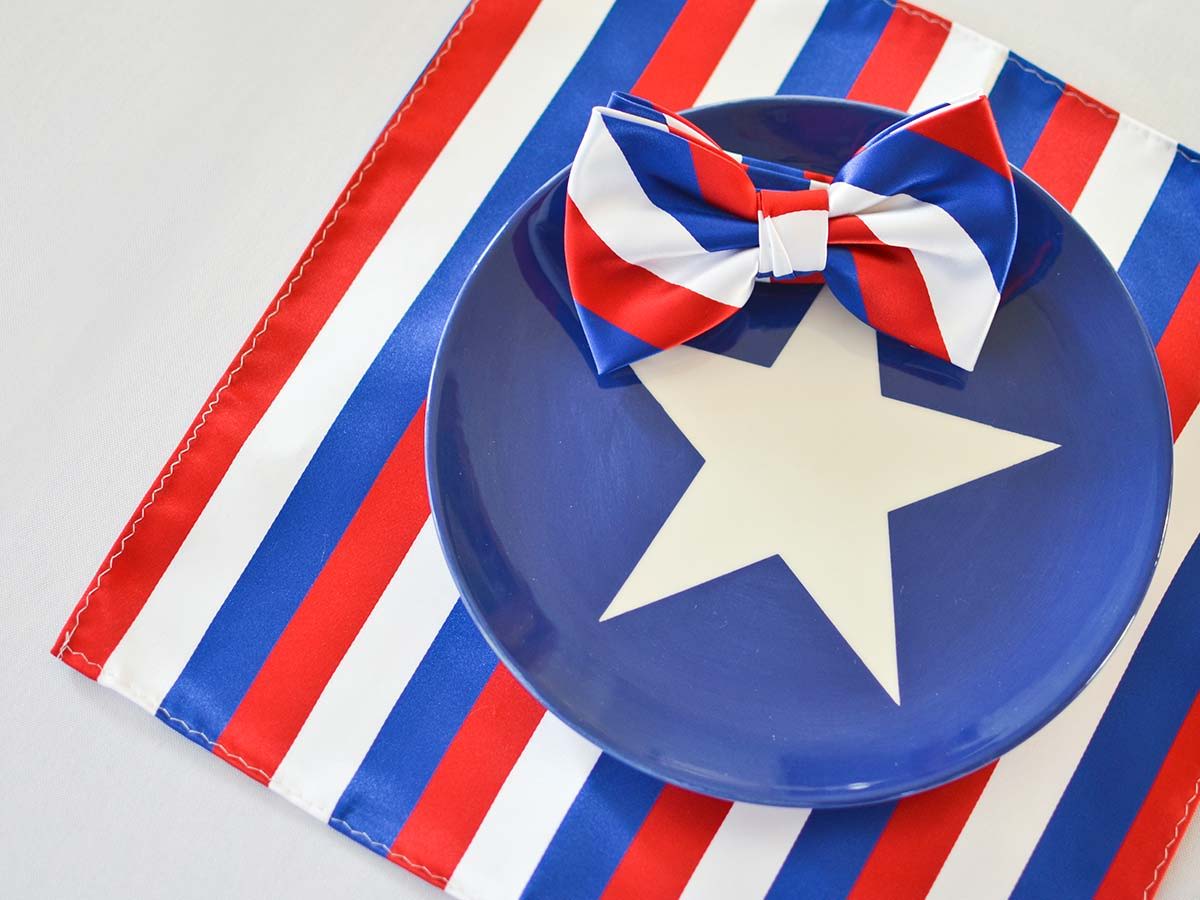 Red, white and blue striped bow tie and pocket square flat lay with a patriotic star plate