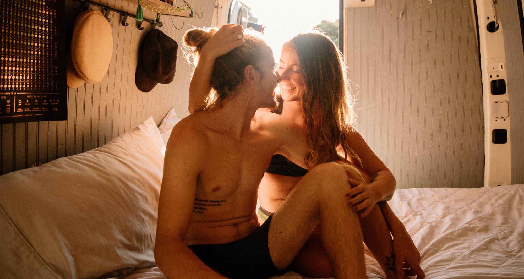 A man and a woman embrace on their van bed, both in anti chafing underwear by WAMA Underwear.