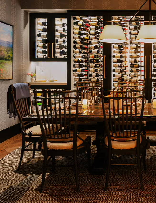 Dining room with wooden chairs and a wine rack on the wall.