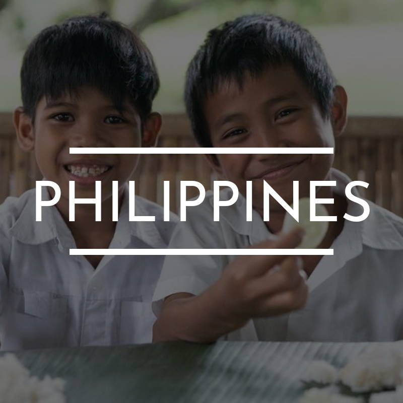 “PHILIPPINES” Is written on top of an image of two young boys sitting together wearing white. 
