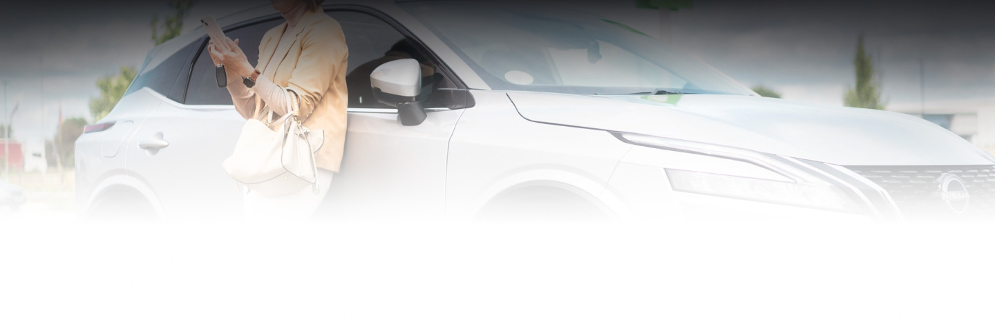 Person using a smartphone next to a white car.