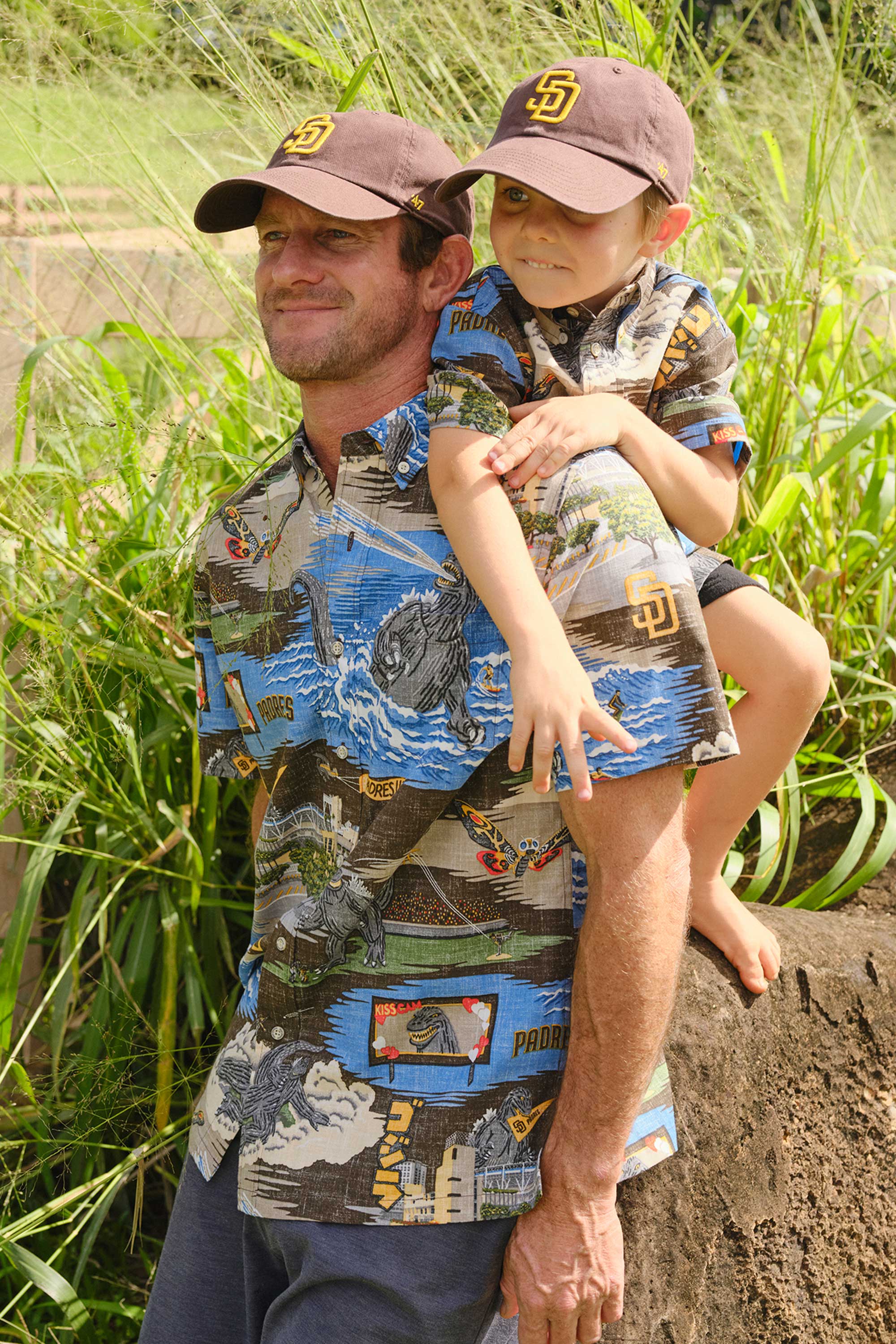 Man carrying a child on his back, both wearing matching shirts and hats.