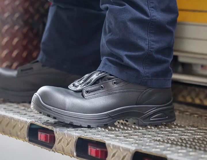 A close-up of a black safety shoe on a step.
