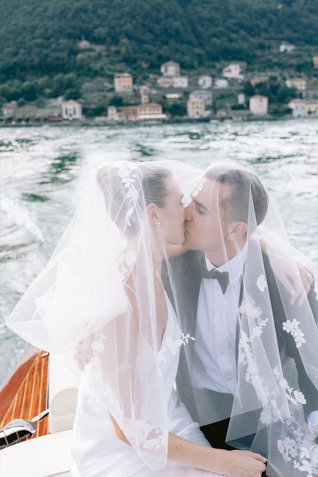 Bride and groom kissing on a boat with scenic background.