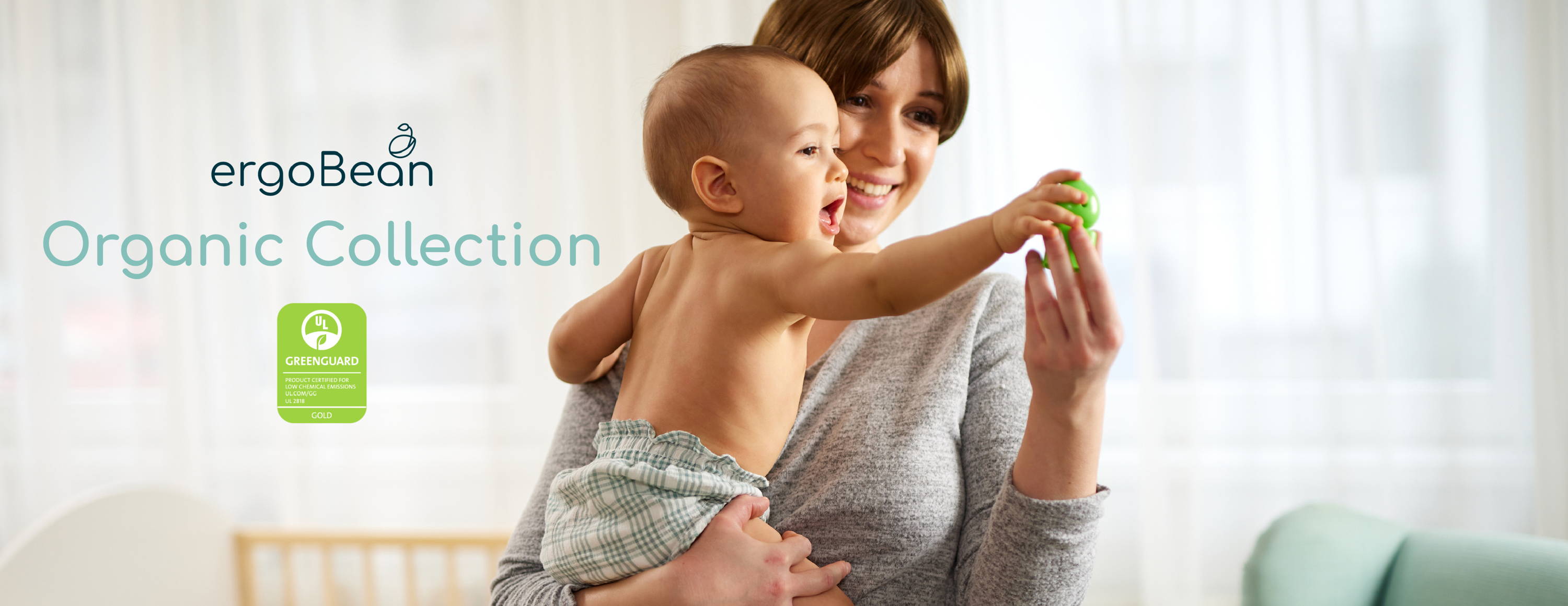 Mom and baby in a nursery with an ergoBean Organic Collection crib mattress in the background.