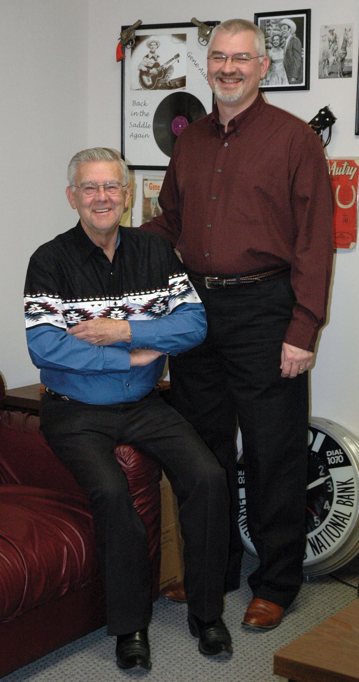 Don and Brett Walton posing together in a cozy room with retro decor.