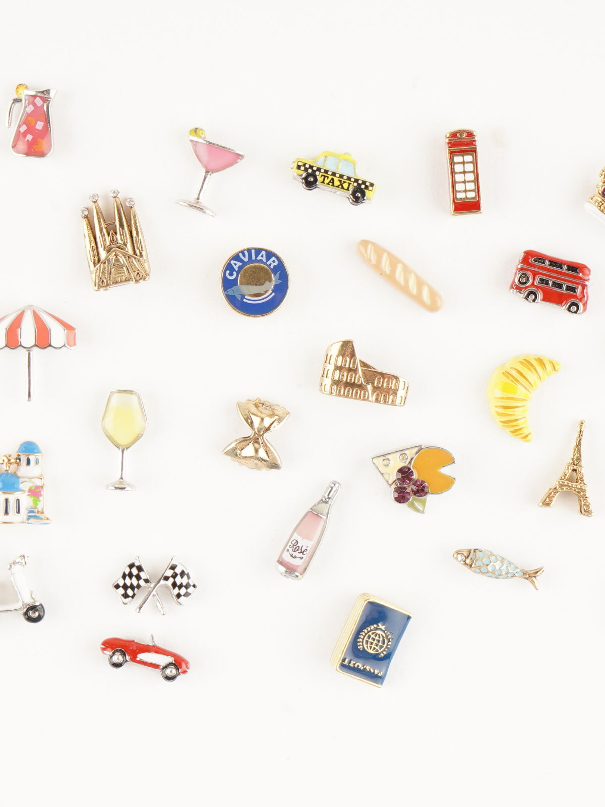Assorted mini charms including travel, food, and lifestyle designs arranged on a light background.