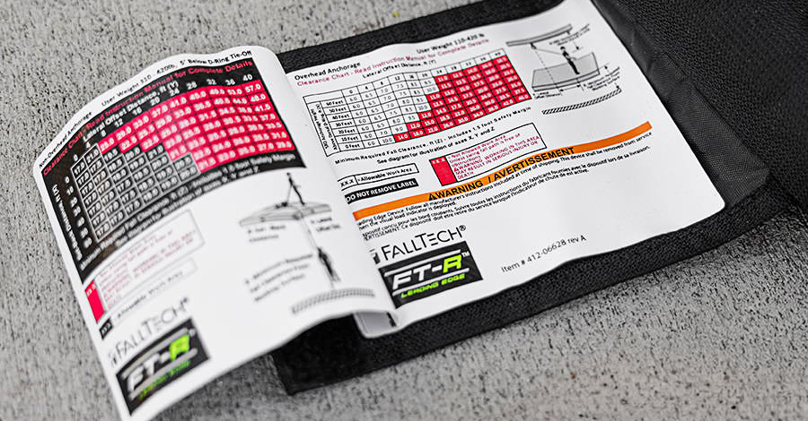 This Class 2 SRL keeps its fall-clearance chart inside the energy absorber cover. ANSI/ASSP Z359.14-2021 requires a chart or diagram on the device and in the user manual but does not require this location.