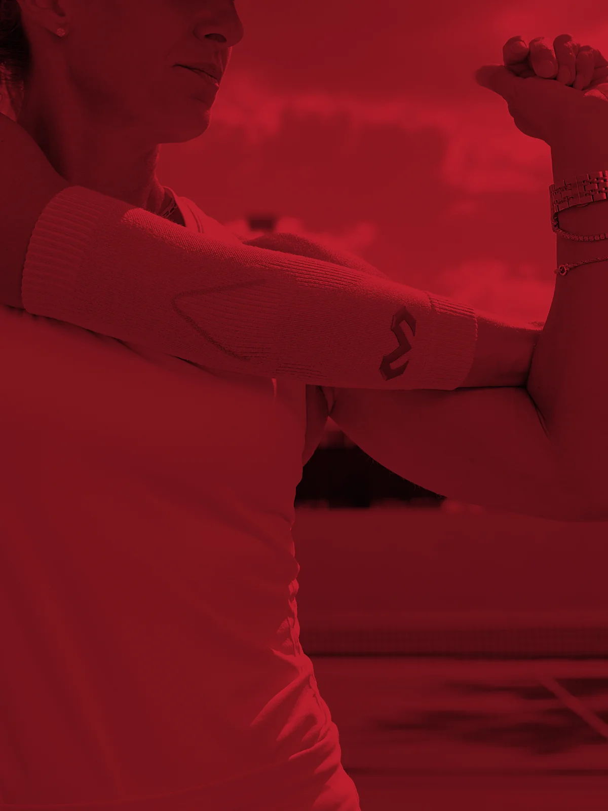 Person stretching their arm with a visible tattoo, against a red background.