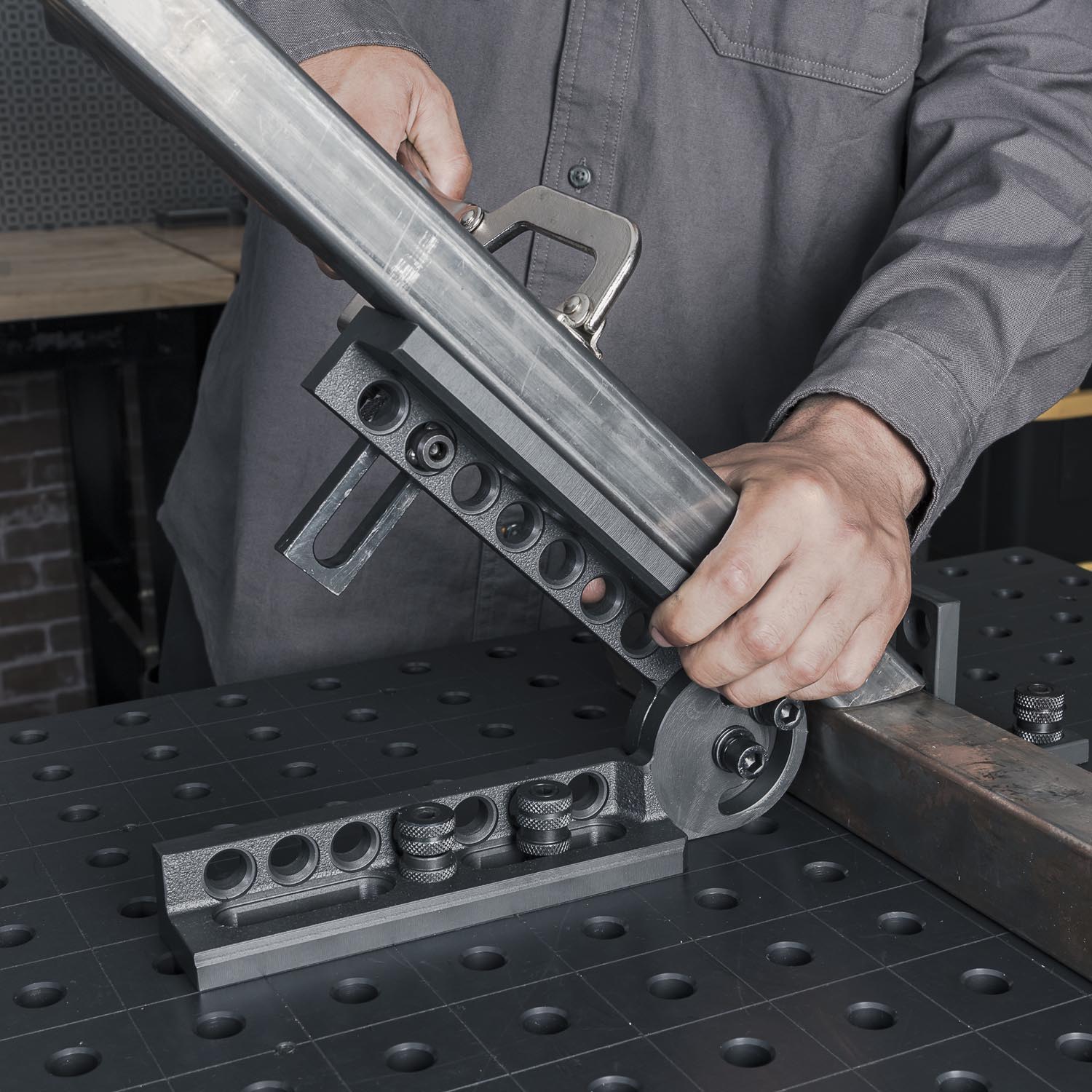 Person using a metalworking tool on a workbench with a modular fixture.