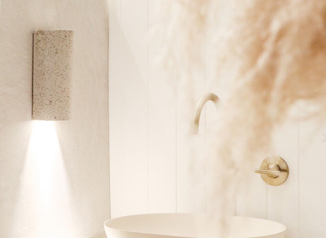 Speckled ceramic wall light on a pale wall above a modern bathroom sink