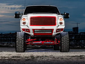 Front view of Corbin's lifted white 2016 Ford F250 with red grille and LED lighting at twilight