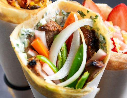 A close-up of a wrap filled with vegetables and meat.