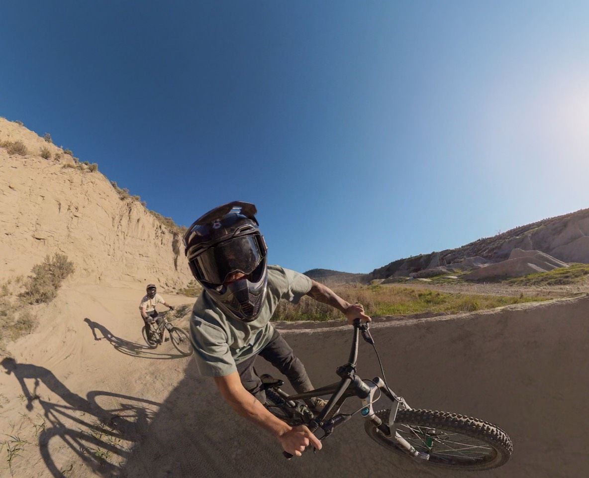 Person riding a bike on a trail with mountains in the background.