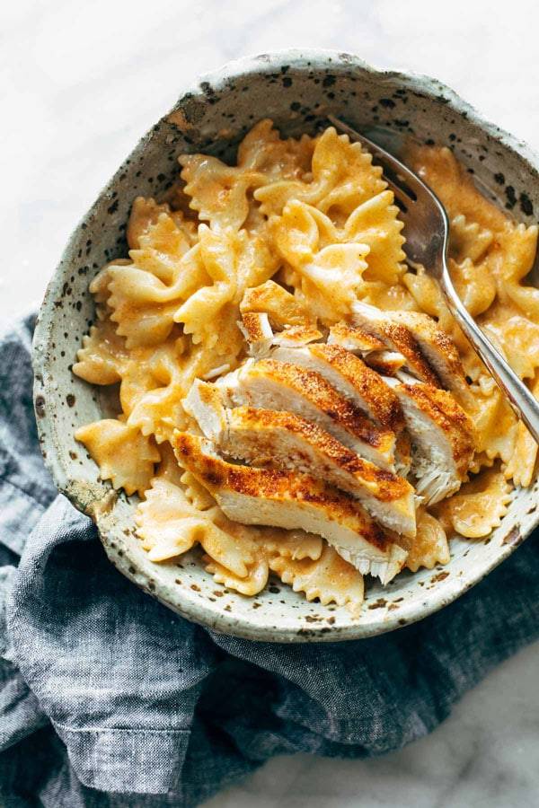 Farfalle pasta in a creamy sauce topped with grilled chicken strips and served in a bowl