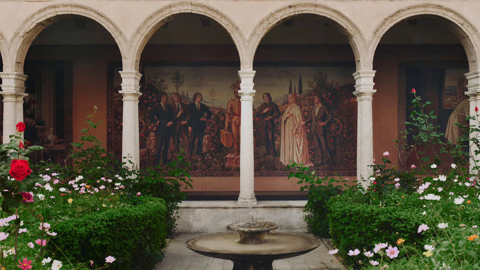 A courtyard with arches, murals, and blooming flowers.