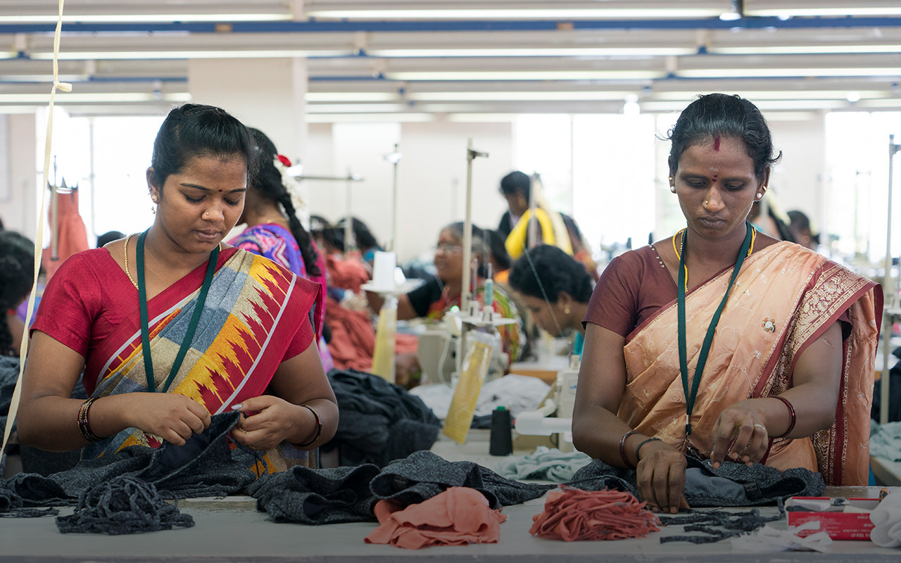 Two factory workers  sewing fabrics.
