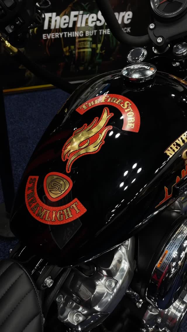 Black motorcycle tank with fire department emblem and text.