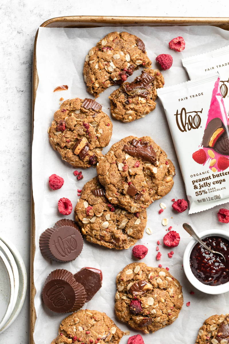 Peanut Butter & Jelly Cup cookies on baking sheet with raspberries and peanut butter & jelly cups.