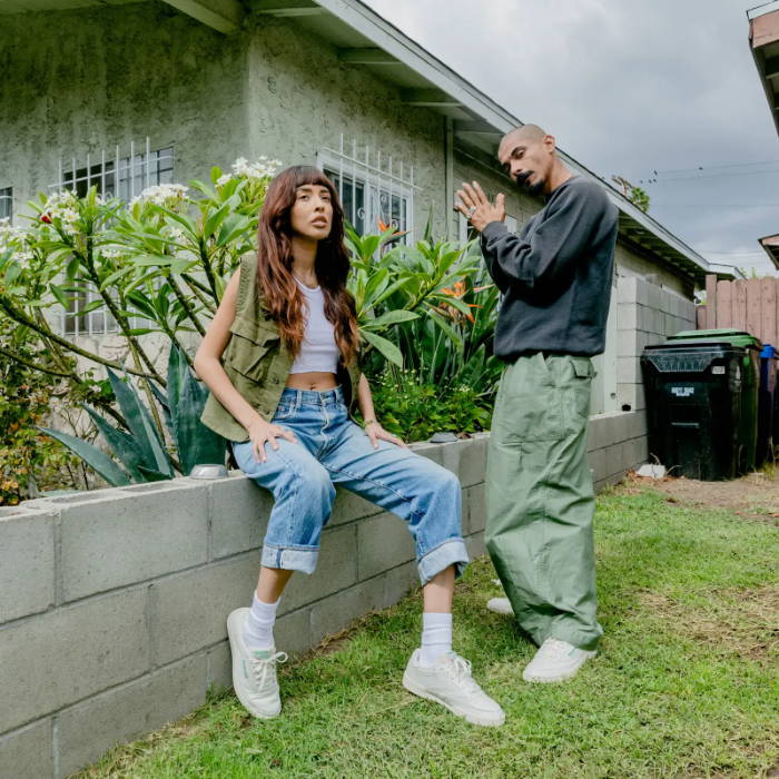 male and female model wearing reebok sneakers in front of hosue