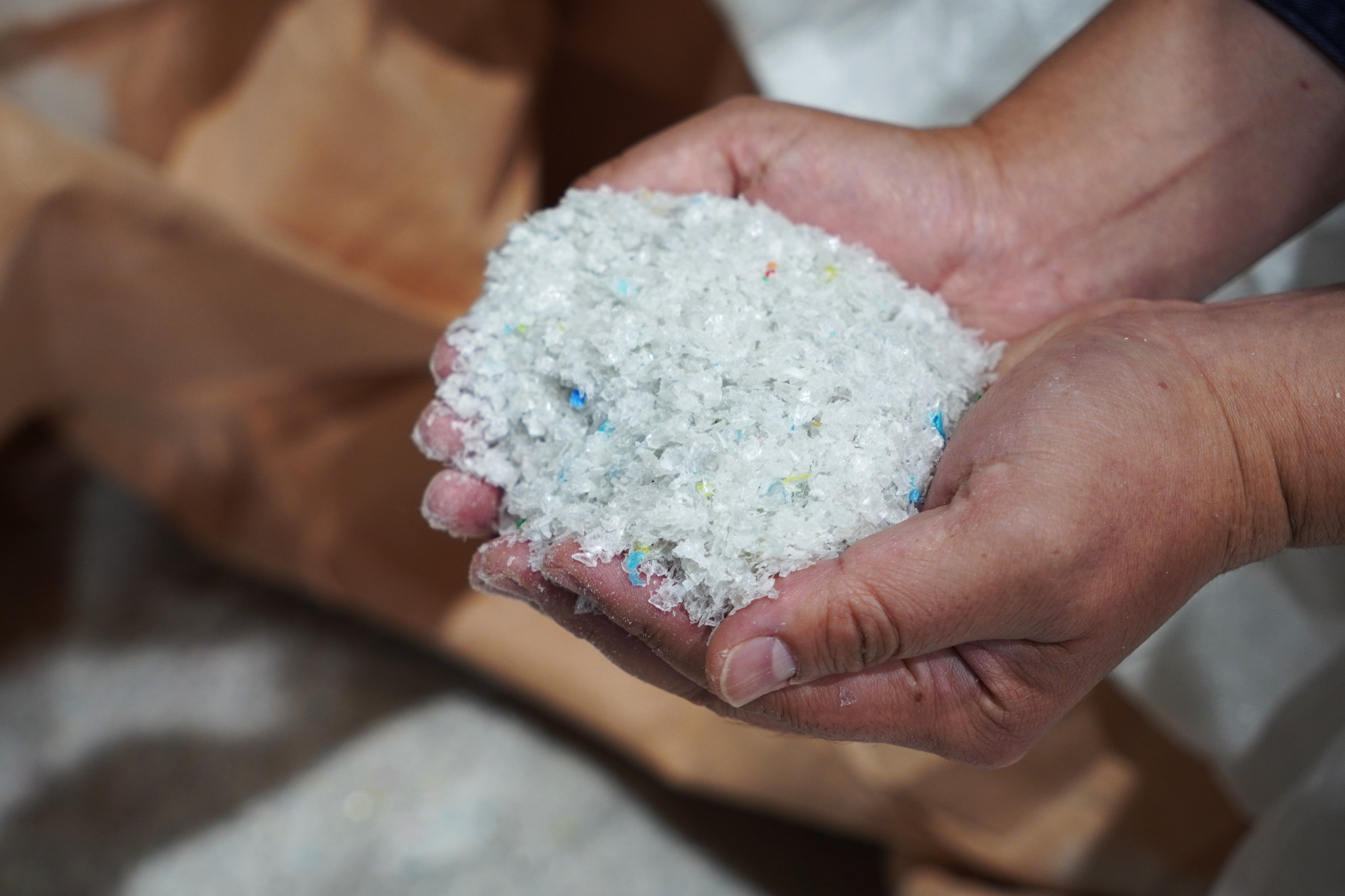 Hands holding a handful of white and blue grains or crystals.