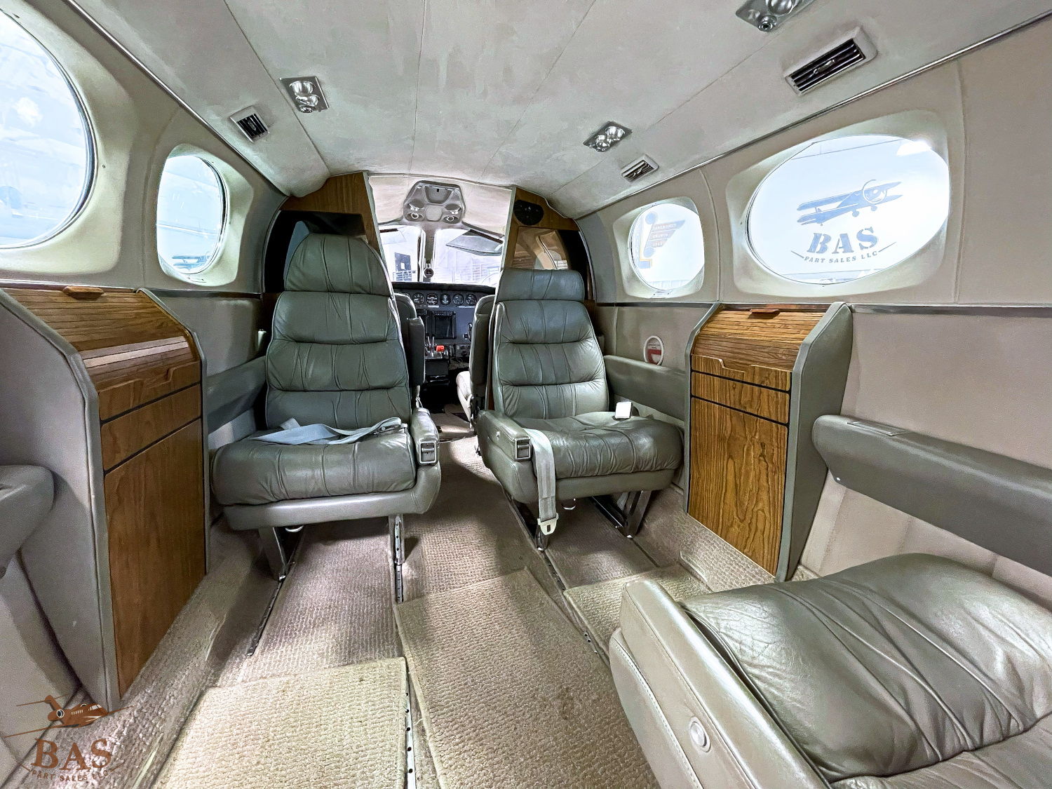 Interior of a private jet with leather seats and large windows.