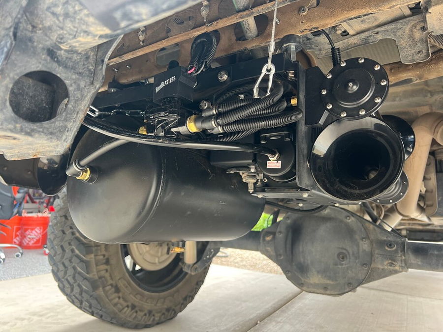 Low-angle under-rear view Stealth Spare Tire Delete kit with black air tank train horns solenoid and wiring mounted in spare tire well Brian's 2022 Chevy Silverado gallery photo 2