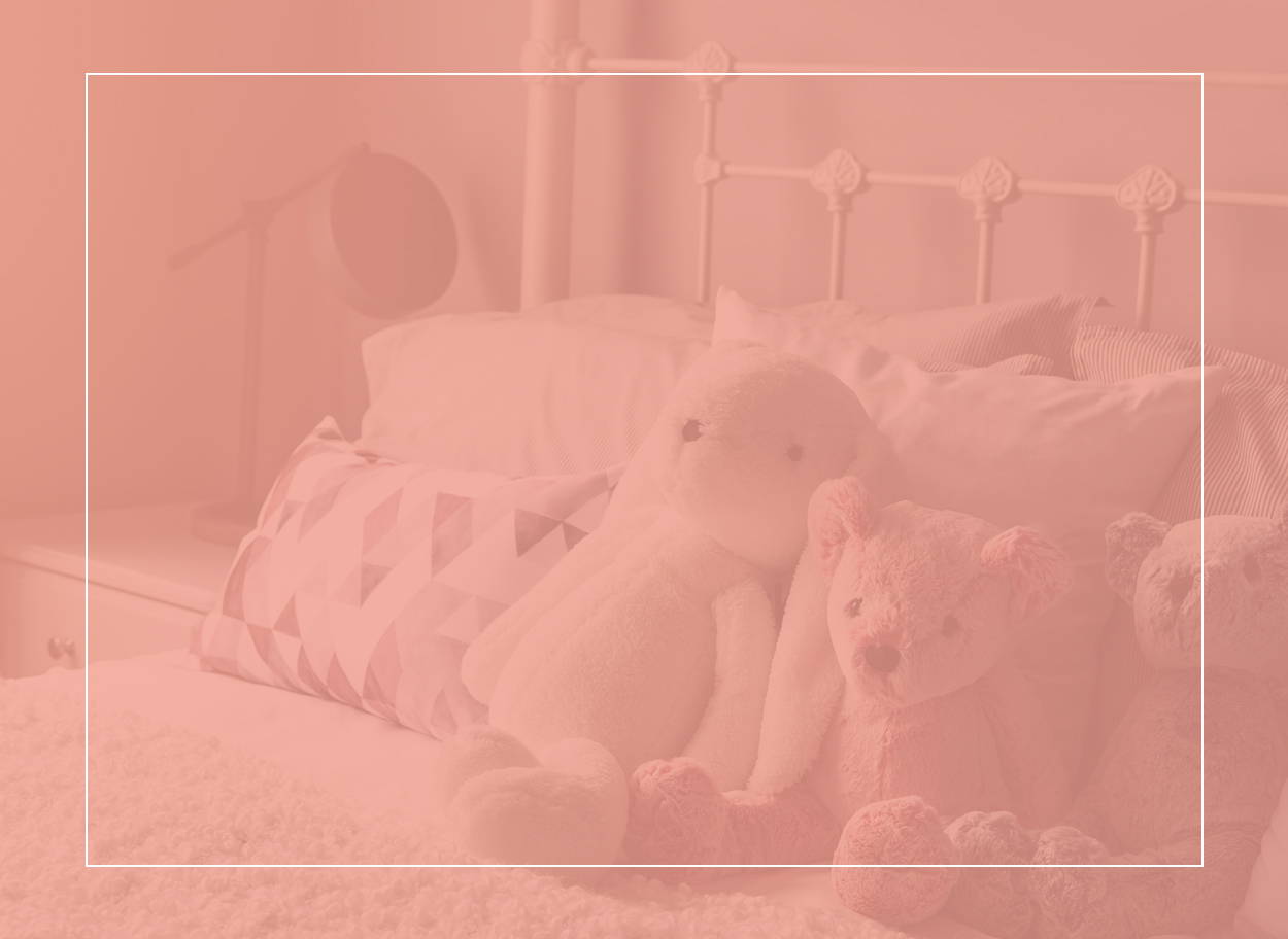 Kuscheltiere und hübsche Kissen auf einem Bett mit weißem Rahmen – ein potenzieller Hotspot für Hausstaubmilben und Symptome für eine Allergie auf Hausstaubmilben.