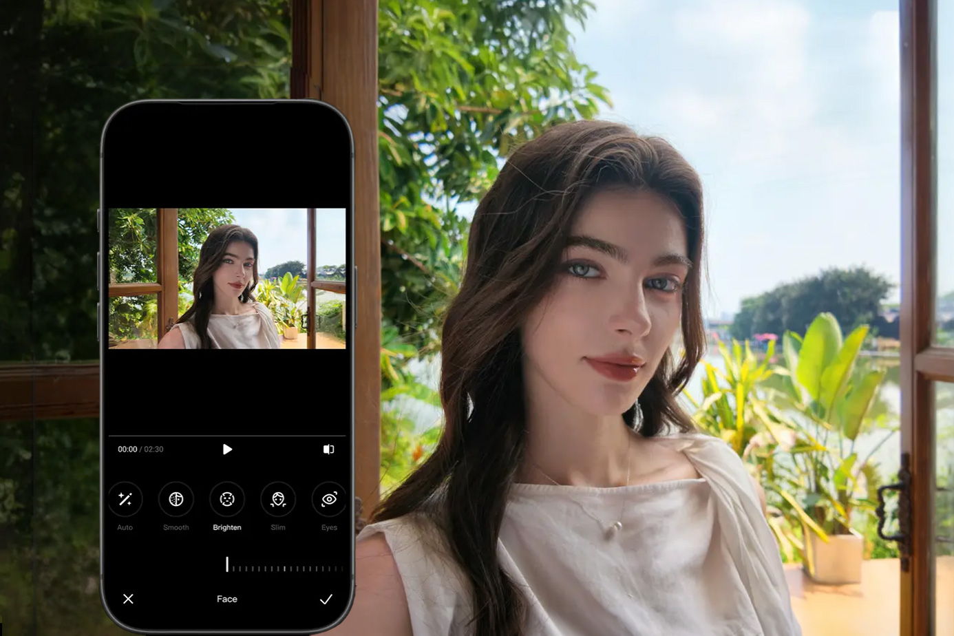 A woman posing with a phone displaying her photo, surrounded by greenery.