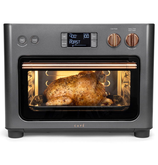 A countertop oven with a roasted chicken visible through the glass door.