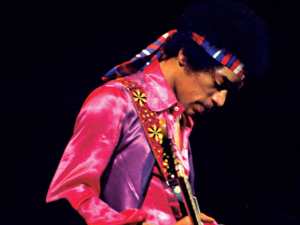 jimi hendrix looking down in pink outfit