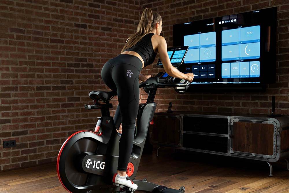 Female riding IC7 Indoor Cycle and screencasting app to TV