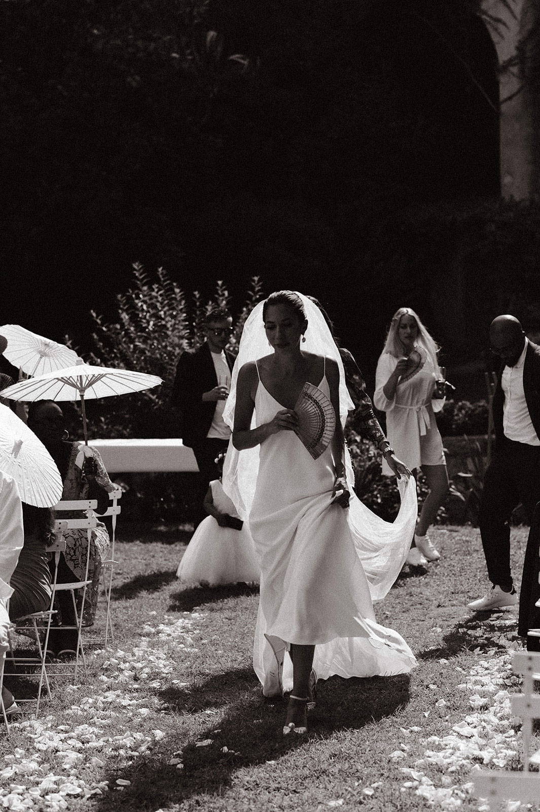 La mariée tient un parapluie et descend l'allée.