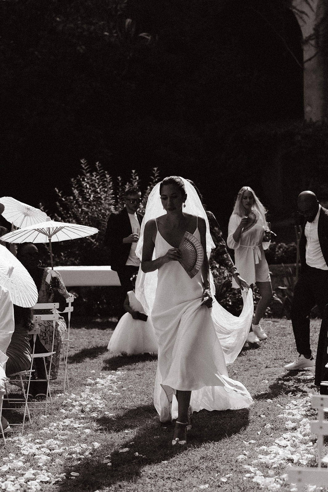 Bride holding umbrella walking down the aisle