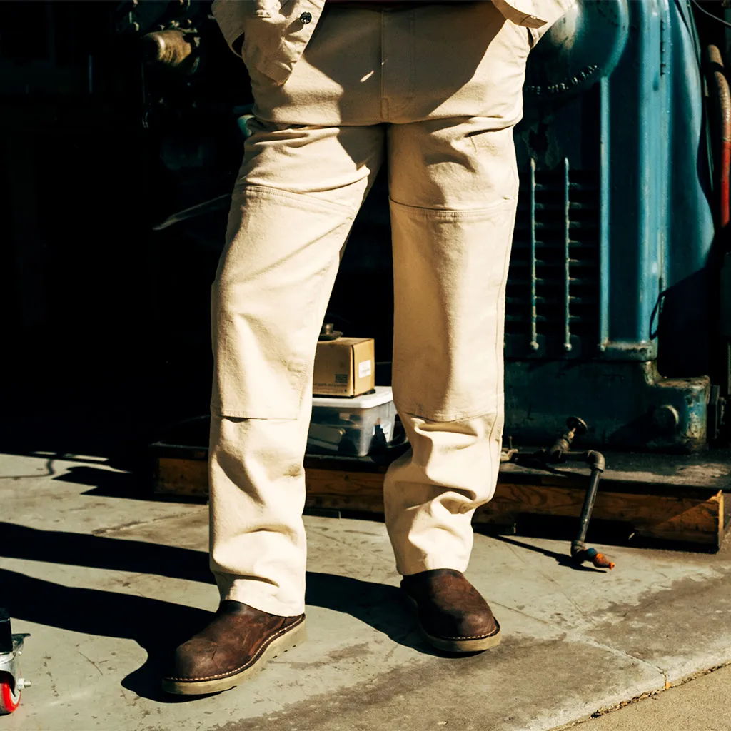 Person standing in light-colored pants and brown shoes on a concrete surface.