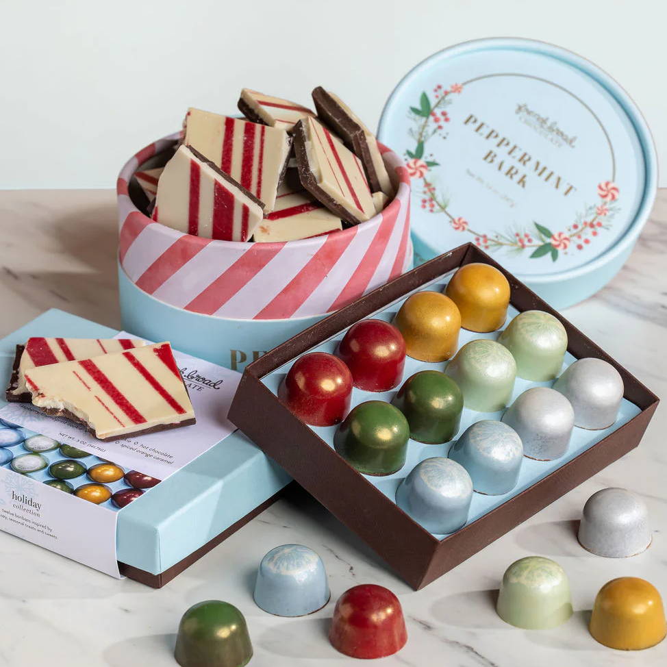 Assorted chocolates and cookies in decorative boxes on a marble surface.